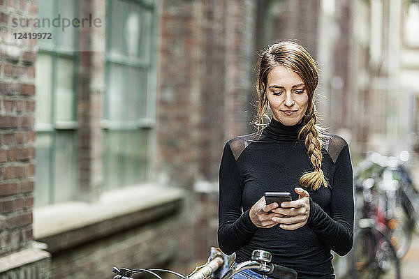 Portrait of woman with bicycle looking at cell phone