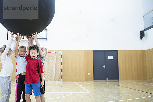 Pupils holding big ball in gym class