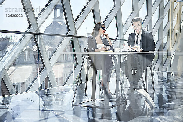 Businesswoman and businessman talking at desk in modern office