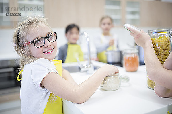 Portrait of smiling schoolgirl with classmtes in cooking class