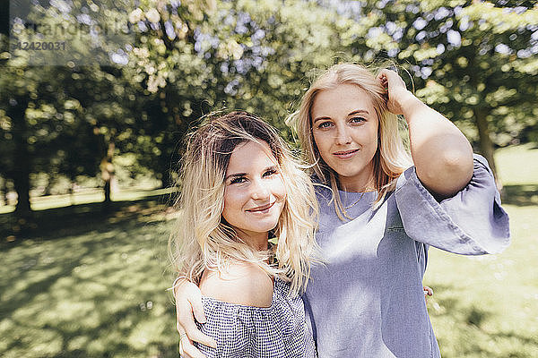 Portrait of two smiling young women embracing in a park