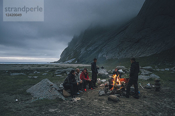Norway  Lofoten  Moskenesoy  Group of young men sitting at a campfire at Bunes Beach