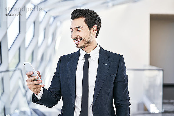 Smiling businessman looking at cell phone