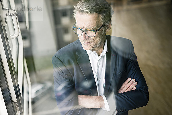 Serious mature businessman looking out of window