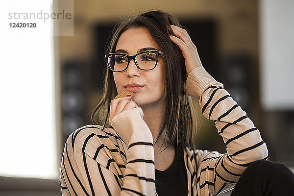 Portrait of fashionable young woman with long brown hair wearing glasses
