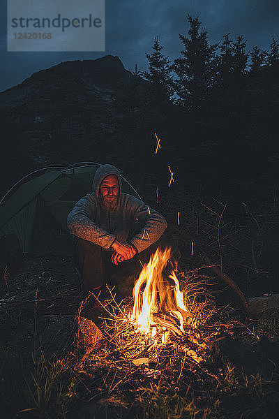 Norway  Lofoten  Moskenesoy  Young man sitting at camp fire