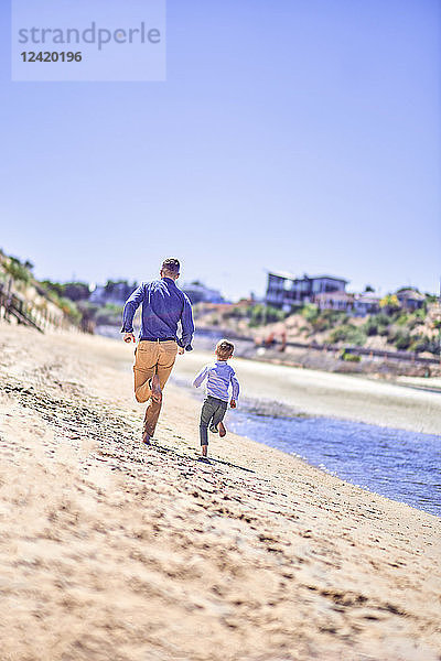 Australia  Adelaide  Onkaparinga River  father and son running on the beach