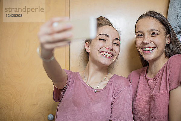 Portrait of two happy teenage girls taking a selfie