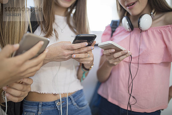 Teenage girls using cell phones in school