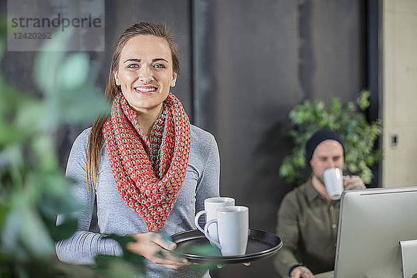 Smiling young woman serving coffee in office