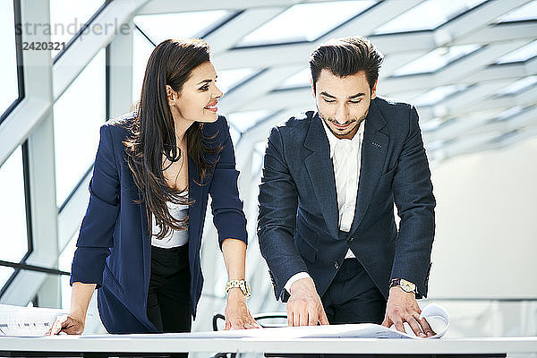 Smiling businesswoman and businessman looking at plan in office