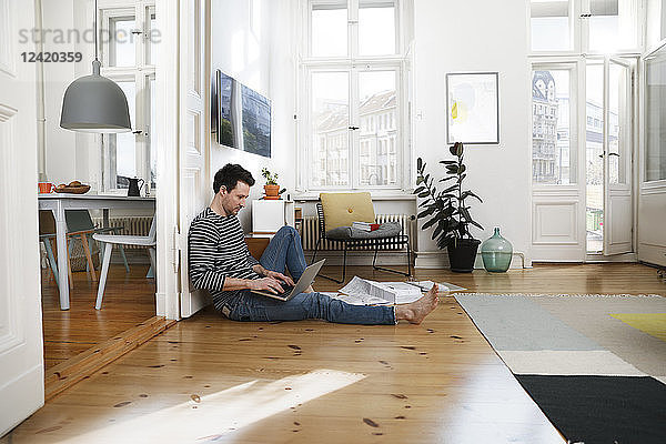 Man sitting in foor  using laptop  working from home