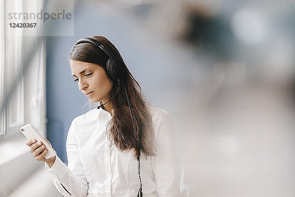 Young woman using smartphone  wearing headset