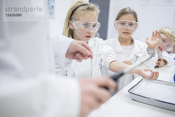 Pupils in science class watching teacher experimenting