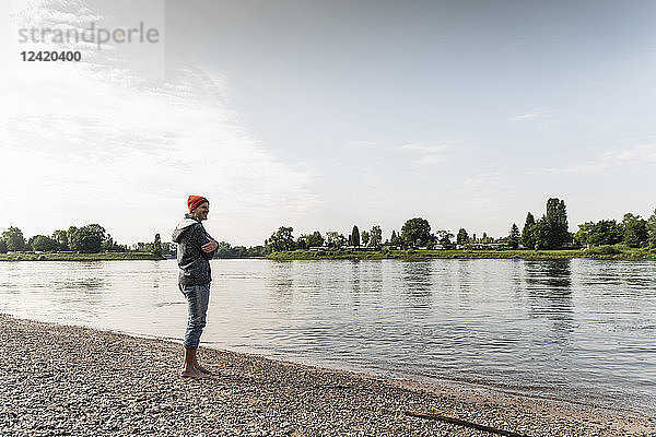 Mature man with red beanie enjoying Rhine riverbank