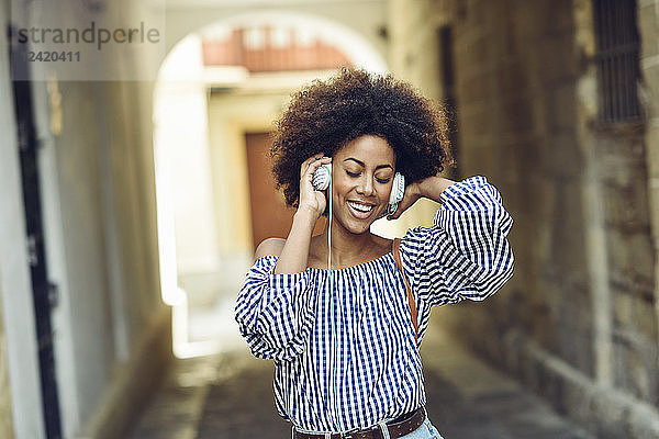 Portrait of happy young woman listening music with headphones