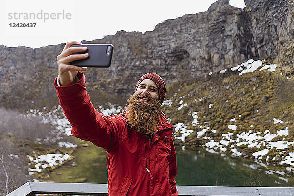 Iceland  smiling bearded man using smartphone  selfie