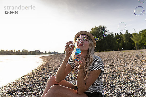 Blond woman blowing soap bubbles at riverside