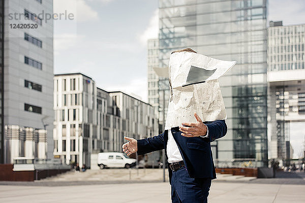 Newspaper covering businessman's face in the city