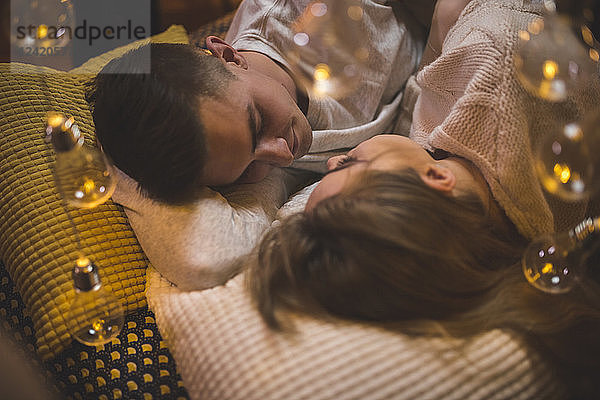 Romantic young couple cuddling in bed with fairy lights