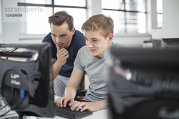 Teacher and student using computer in class