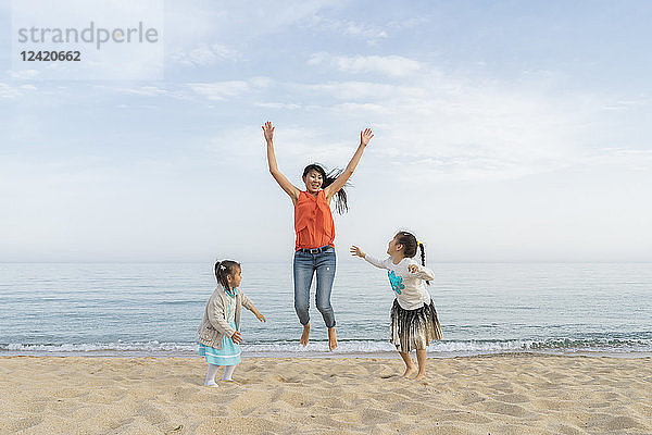 Happy mother with two daughters playing on the beach