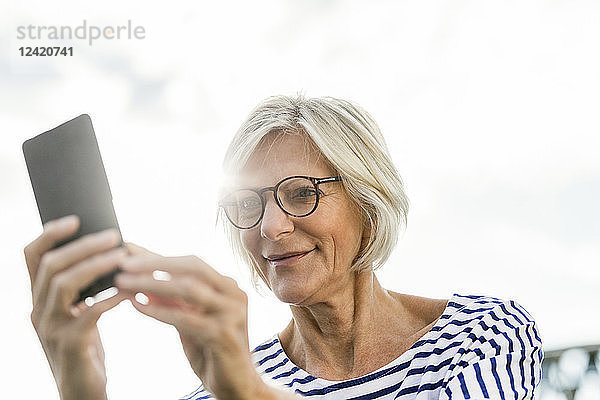 Smiling senior woman using cell phone outdoors