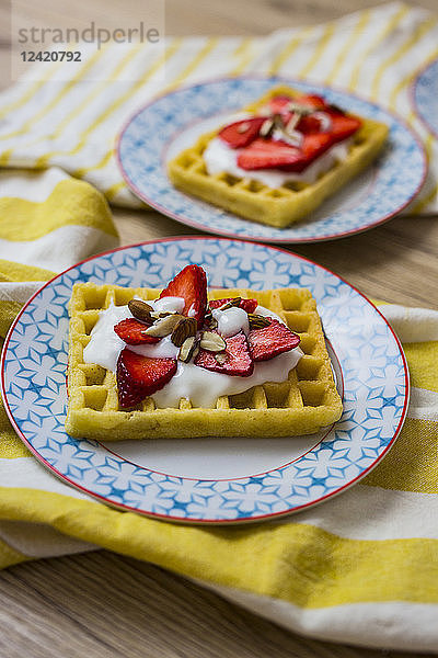 Waffle garnished with strawberries  Greek yogurt and almonds on plate