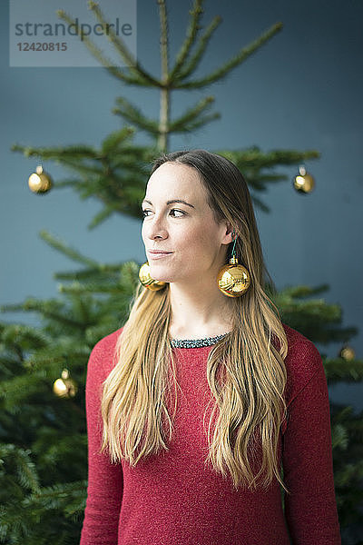 Portrait of woman wearing golden Christmas baubles earrings