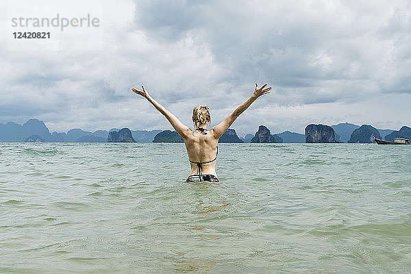 Thailand  Koh Yao Noi  back view of happy woman standing in the sea