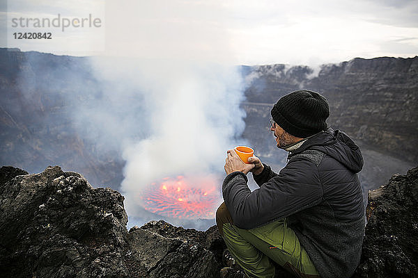 Africa  Democratic Republic of Congo  Virunga National Park  Man sittiing over Nyiragongo volcano crater