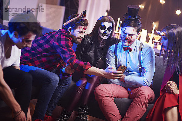 Friends using mobile phone at Halloween party
