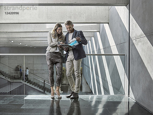 Man and woman sharing booklet on office floor