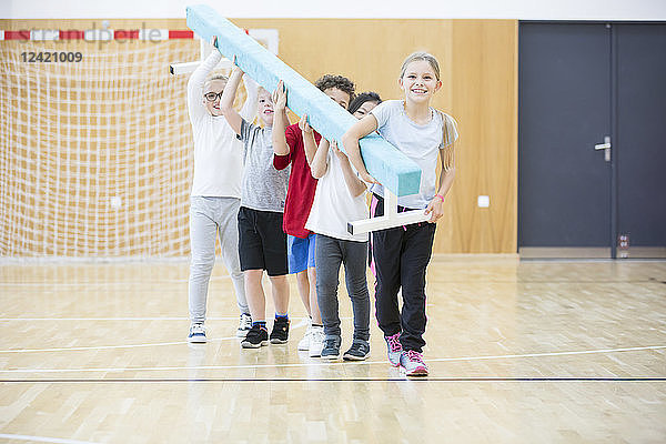Pupils carrying balance beam in gym class