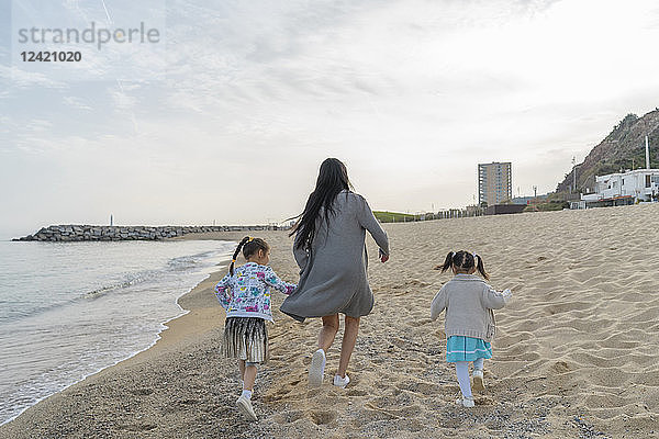 Mother with two daughters running on the beach