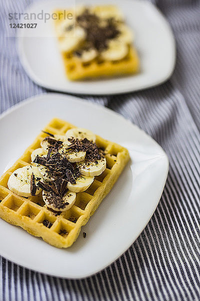 Waffle garnished with banana and chocolate shaving on plate