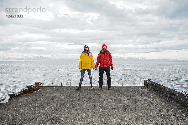 Iceland  North of Iceland  young couple standing hand in hand on jetty