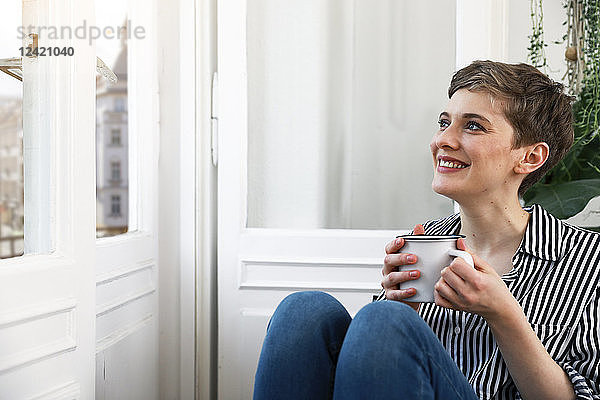 Happy woman sitting relaxed at window  drinking coffee