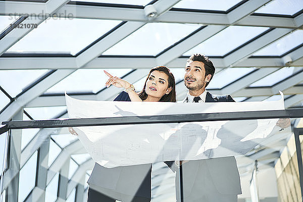 Businesswoman and businessman with plan talking in office