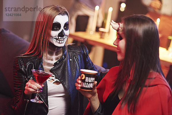 Women in creepy costume drinking at party