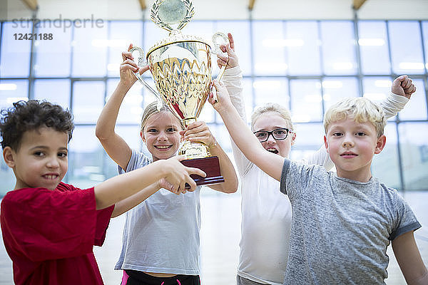 Happy pupils holding trophy in gym