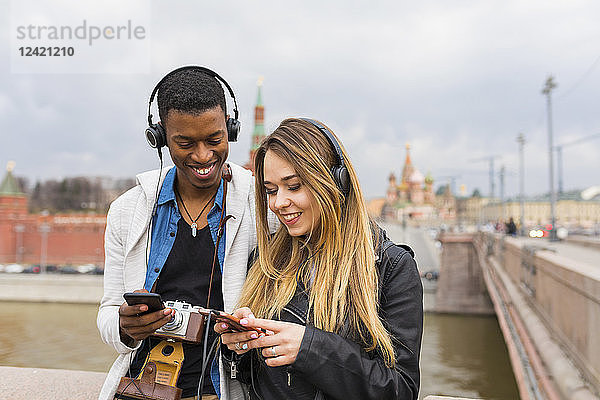 Russia  Moscow  multiracial best friends listening music with headphones