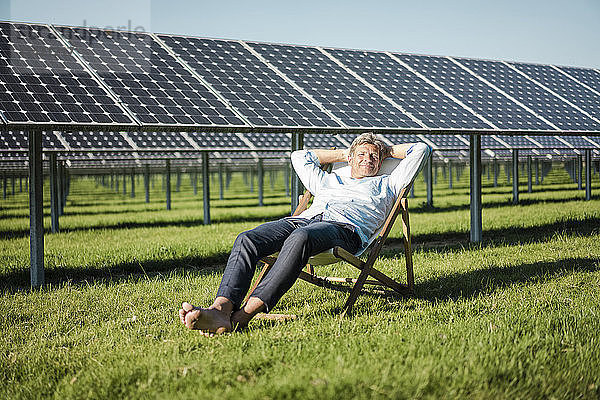 Mature man sitting in sun lounger  solar plant
