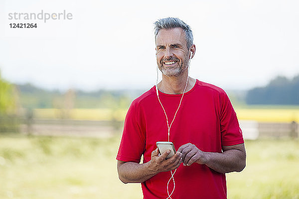 Smiling mature man with smartphone and earphones