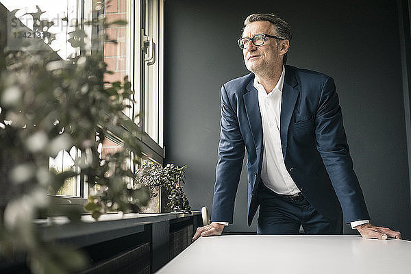 Confident mature businessman looking out of window