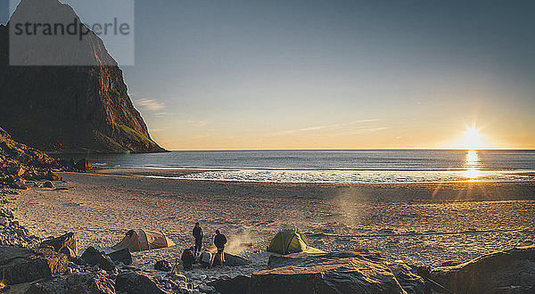 Norway  Lofoten  Moskenesoy  Group of young men camping at Kvalvika Beach