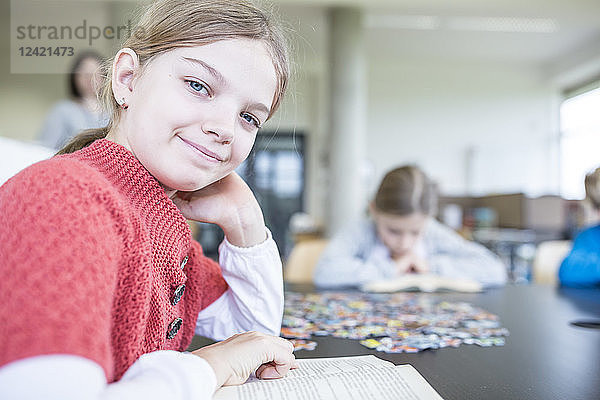 Portrait of smiling schoolgirl with book in school break room