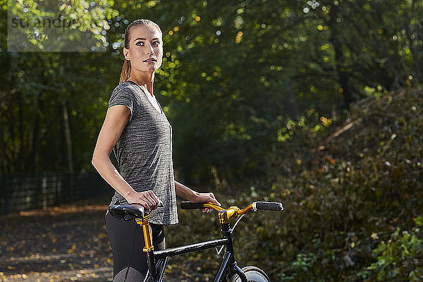 Portrait of sportive young woman with bicycle in a forest