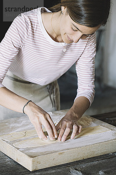 Woman preparing ravioli  pasta dough cutting out on pastry board