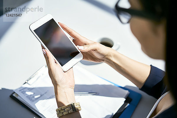 Close-up of businesswoman using cell phone at desk in office